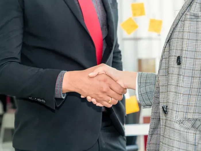 Business handshake between professionals in suits with yellow sticky notes in Town Directory Map